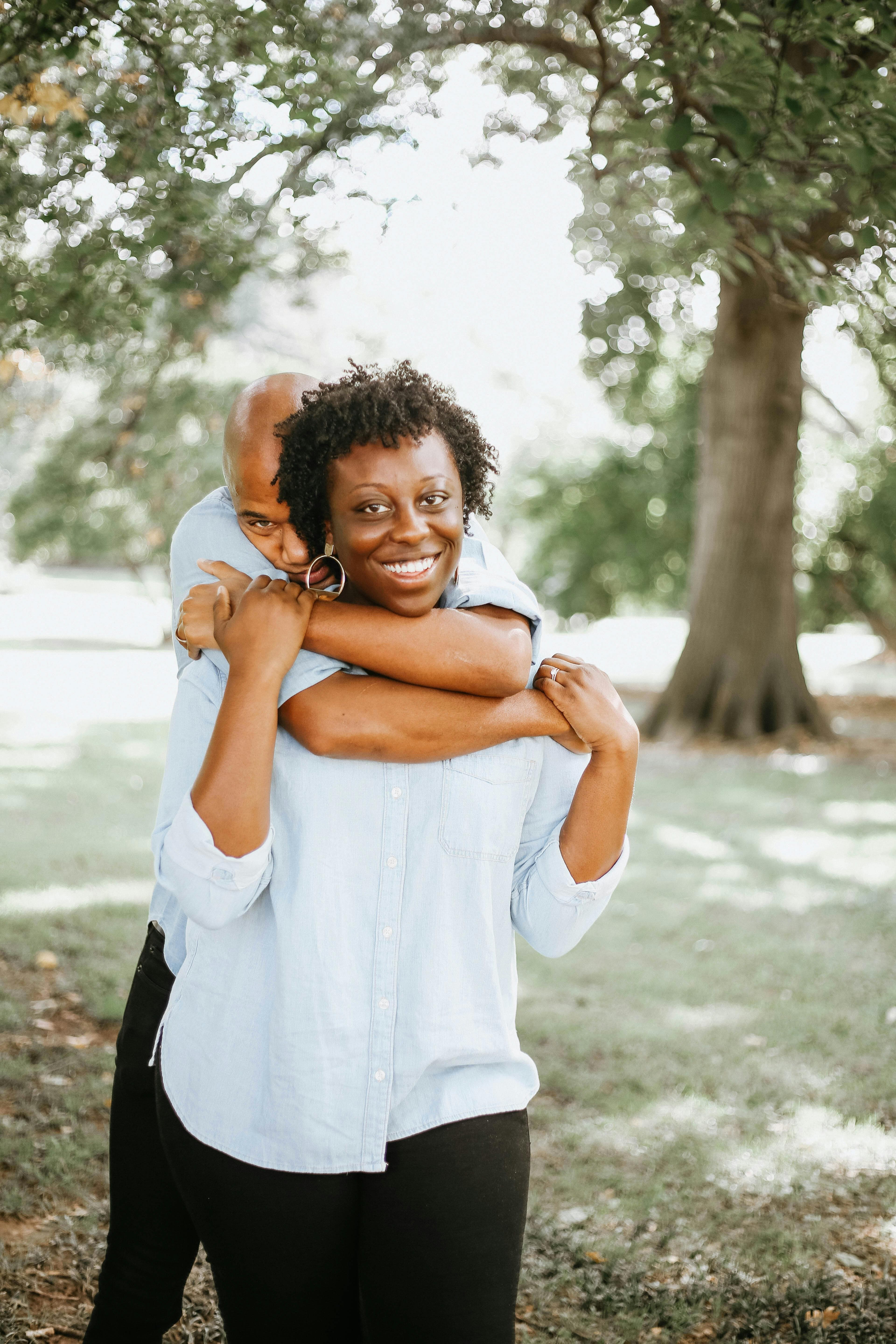 Free Joyful African American couple embracing in a sunny park. Casual and warm atmosphere. Stock Photo