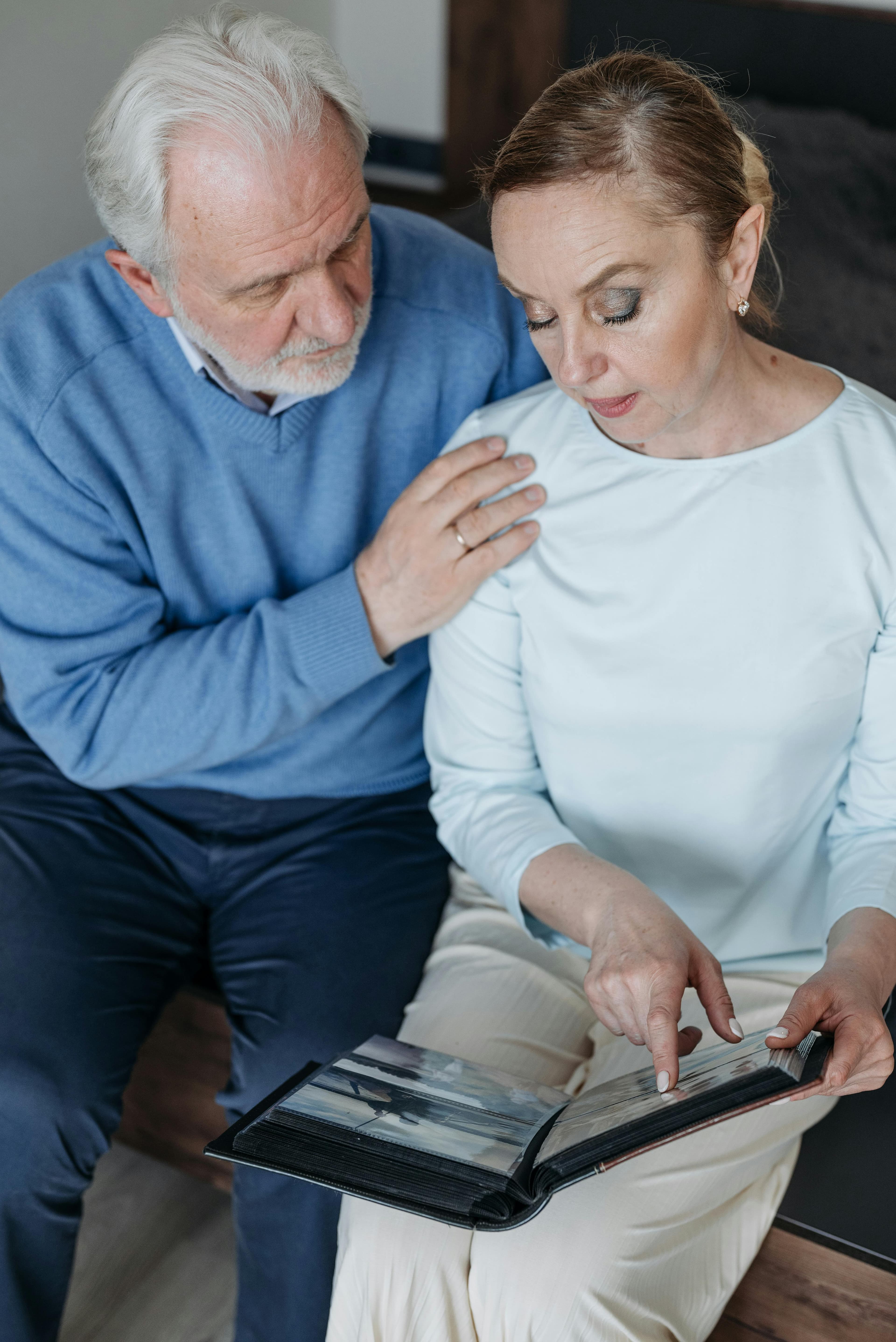 Free Senior couple sharing memories while looking through a photo album indoors. Stock Photo